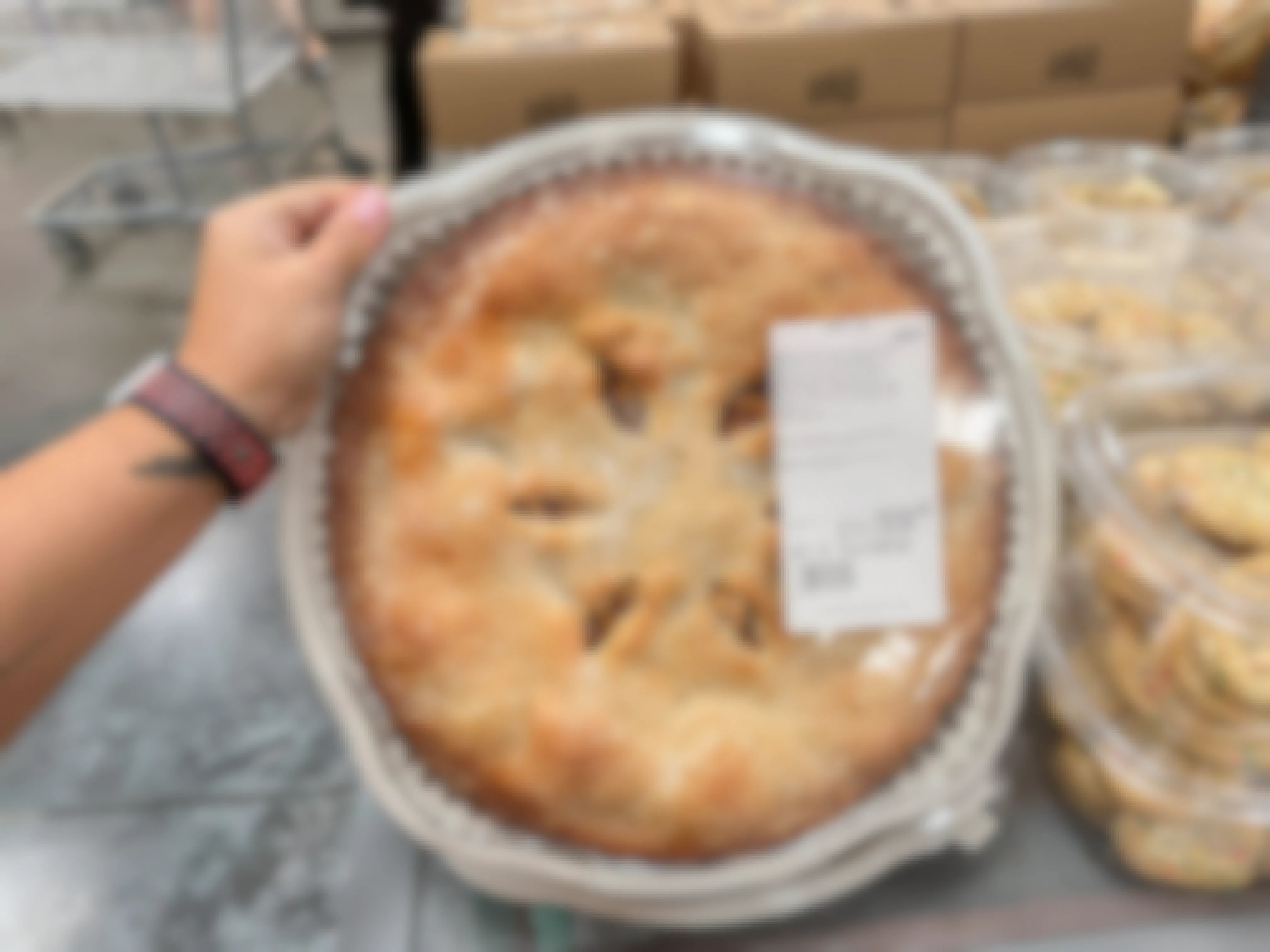 a person holding up an apple pie at costco