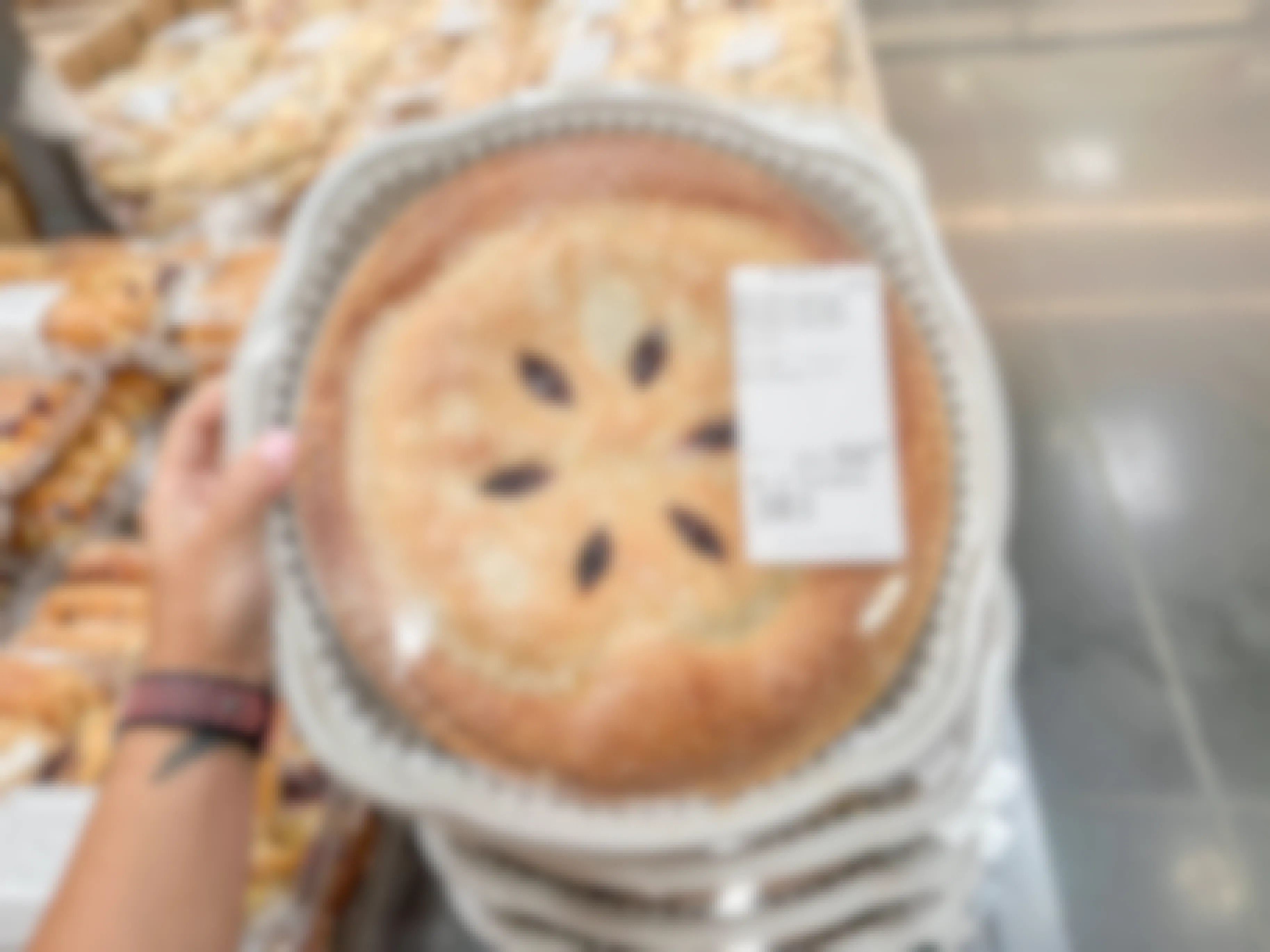 a person holding up a four berry pie at costco
