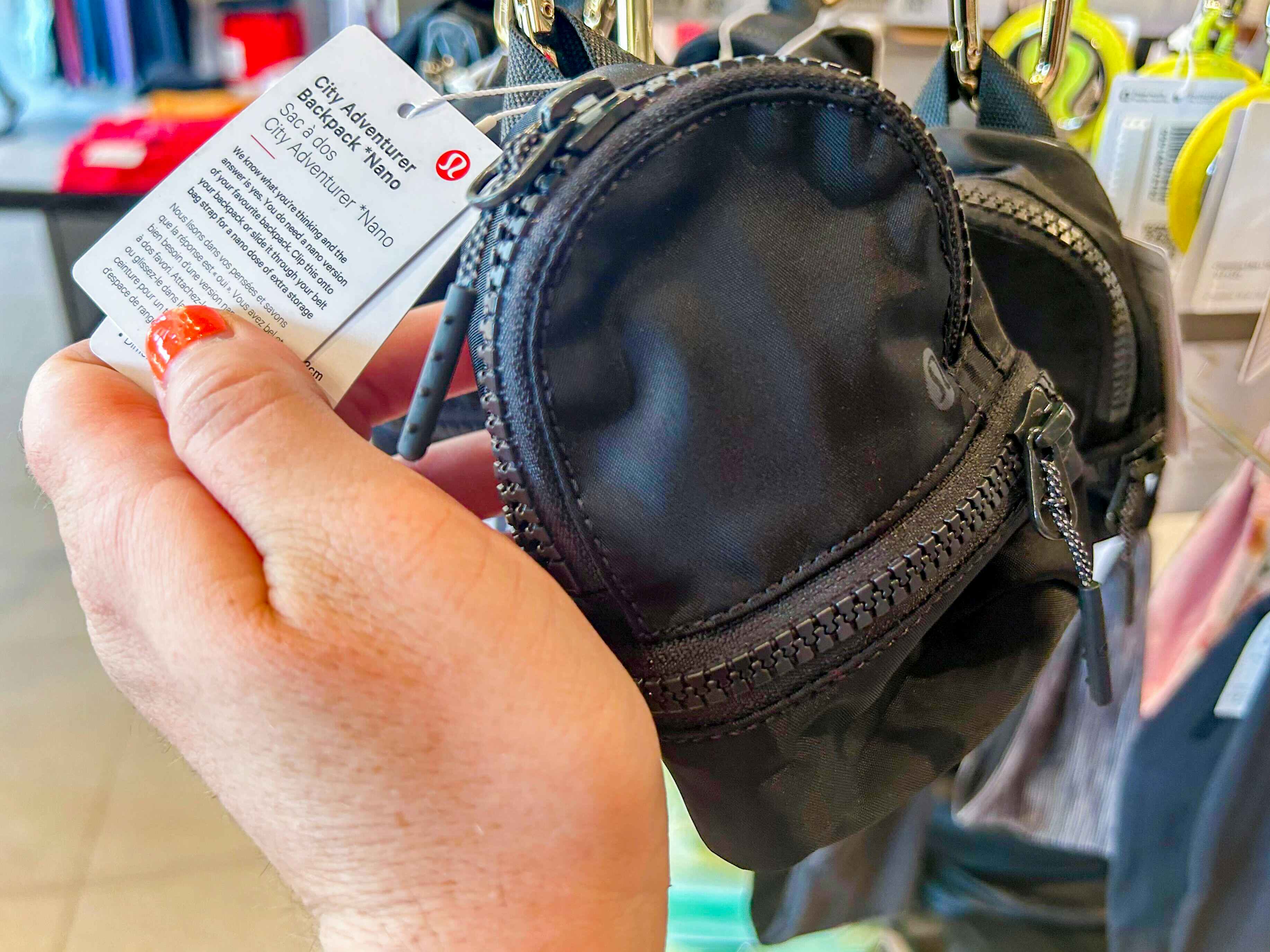 a person holding up a lululemon nano city adventurer backpack in a lululemon store