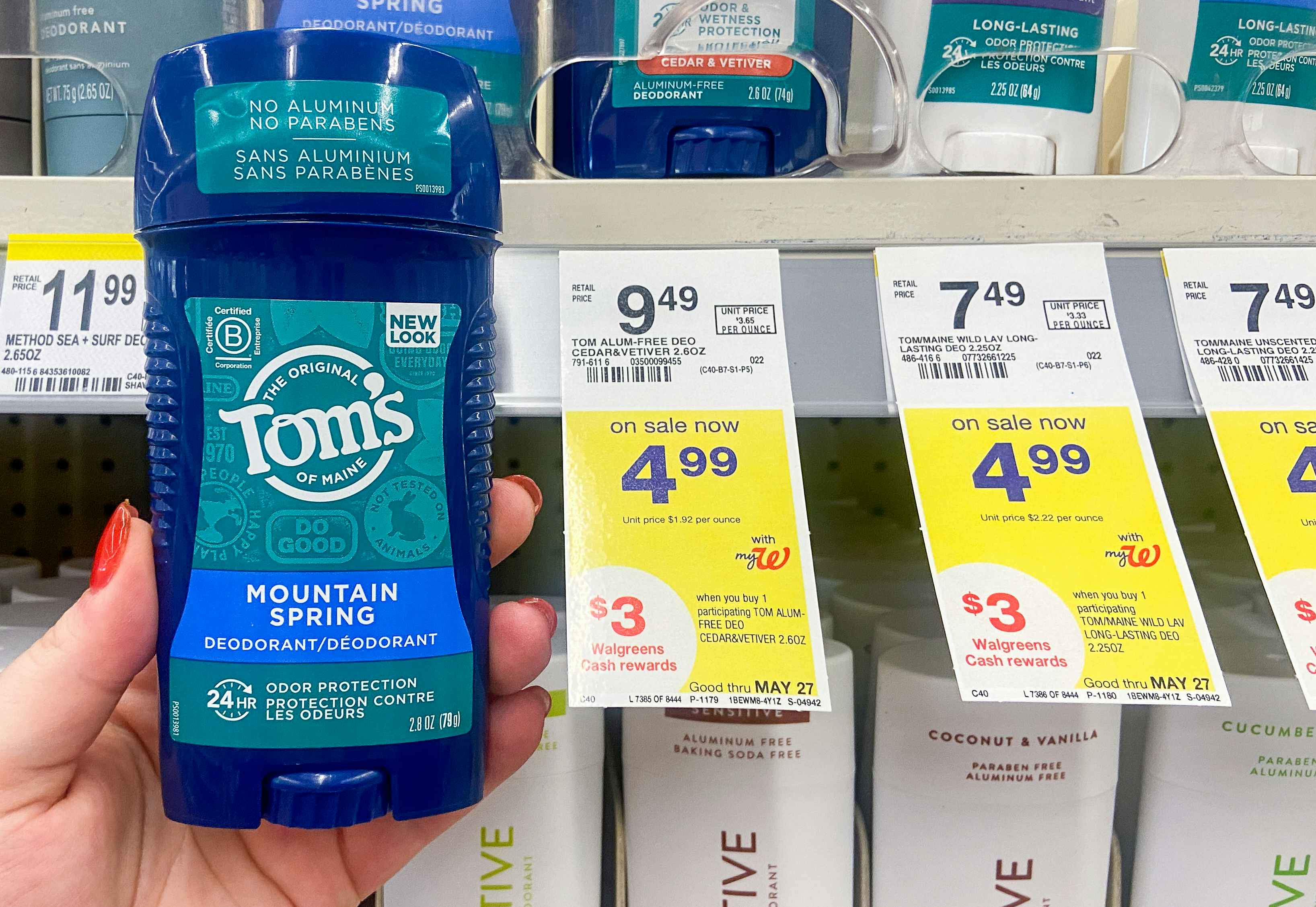 hand holding a stick of tom's of maine deodorant next to walgreens sale tags
