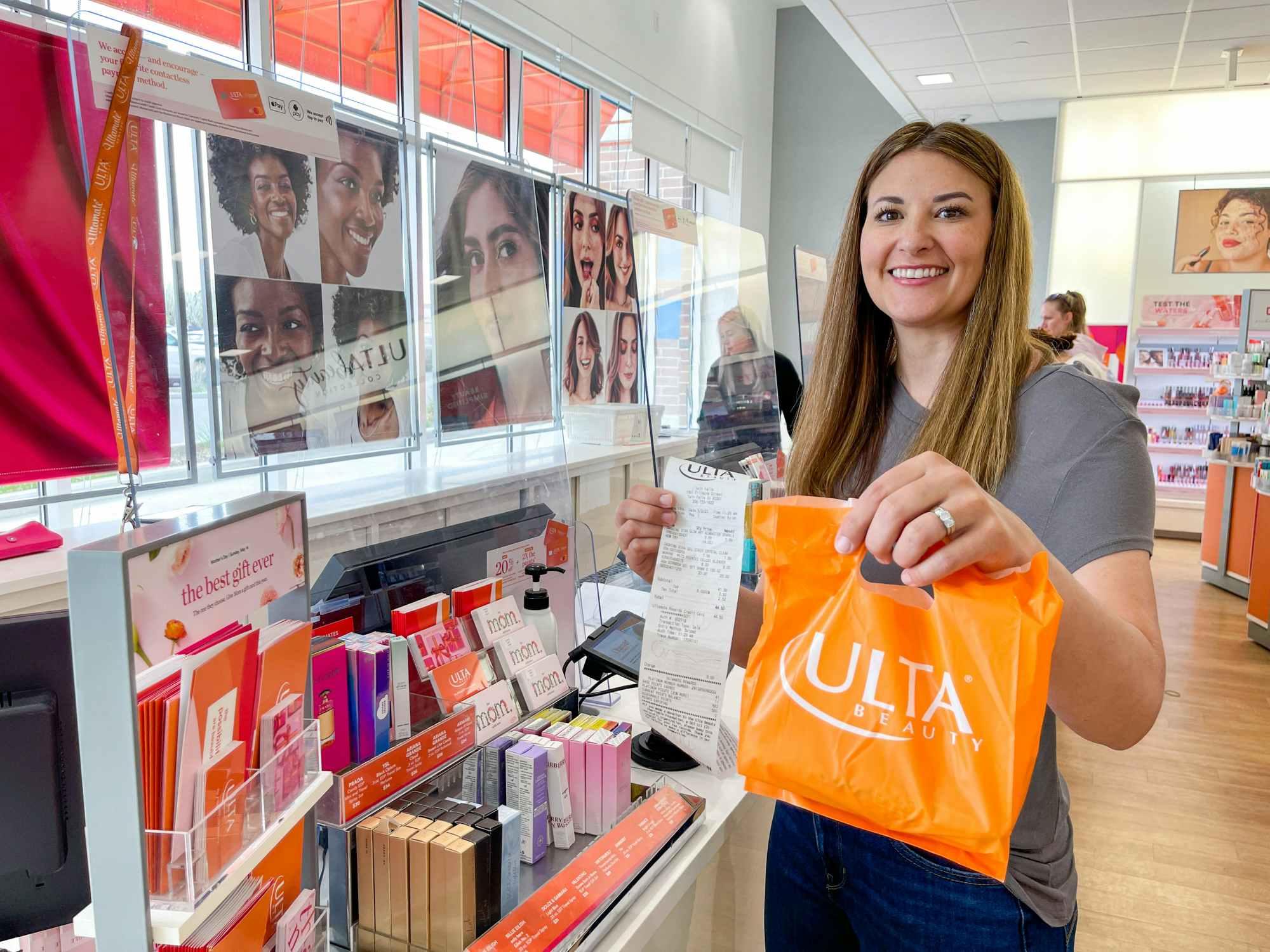 A person holding up a bag of items purchased and receipt from Ulta inside of an Ulta store