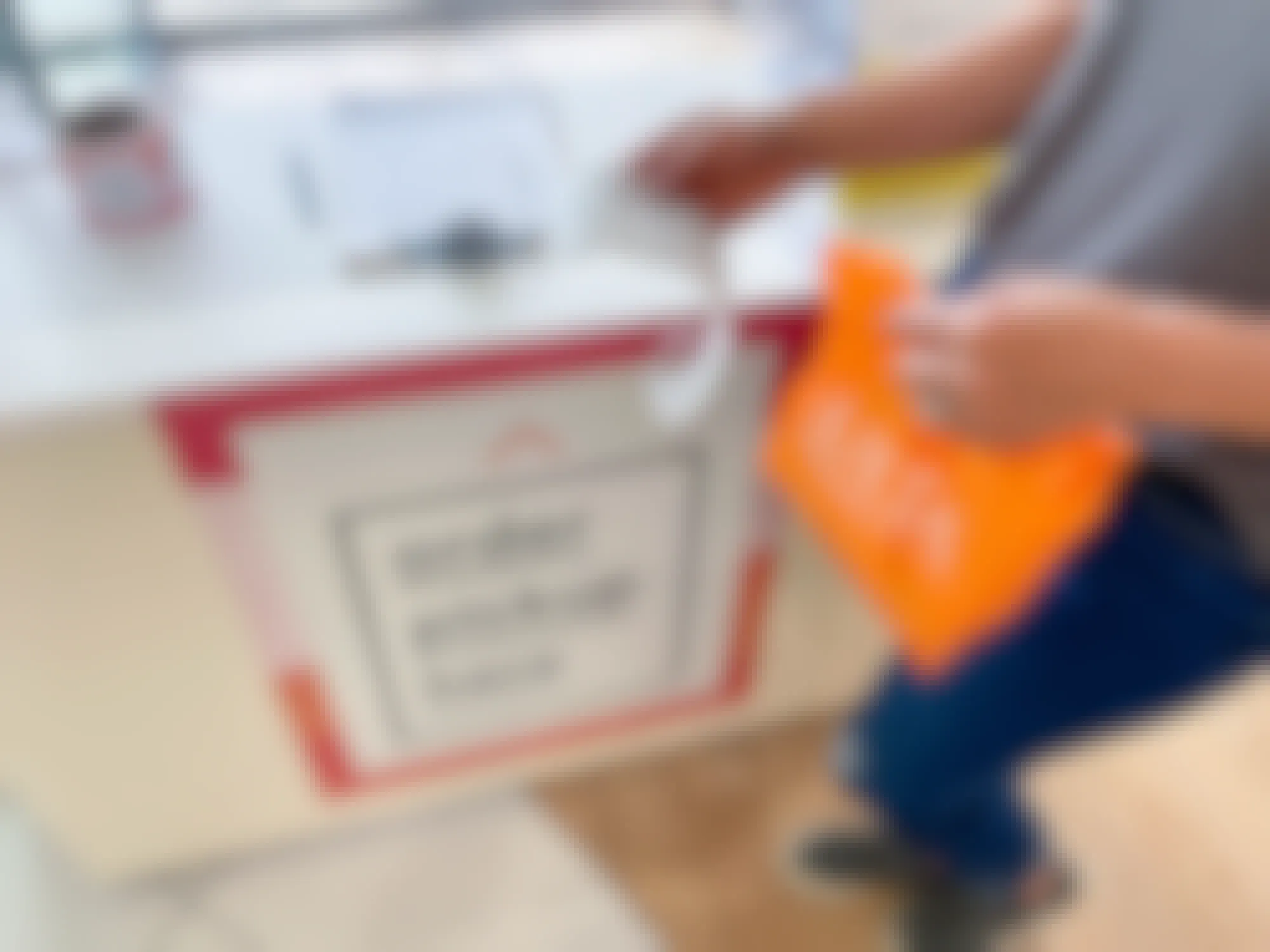 A person holding up a bag of items purchased and receipt from Ulta near the Order Pickup counter of an Ulta store