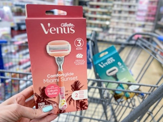 A box of a Venus Miami Sunset razor held out in front of a shopping cart with a Venus Miami Sunrise sitting in the shopping cart.