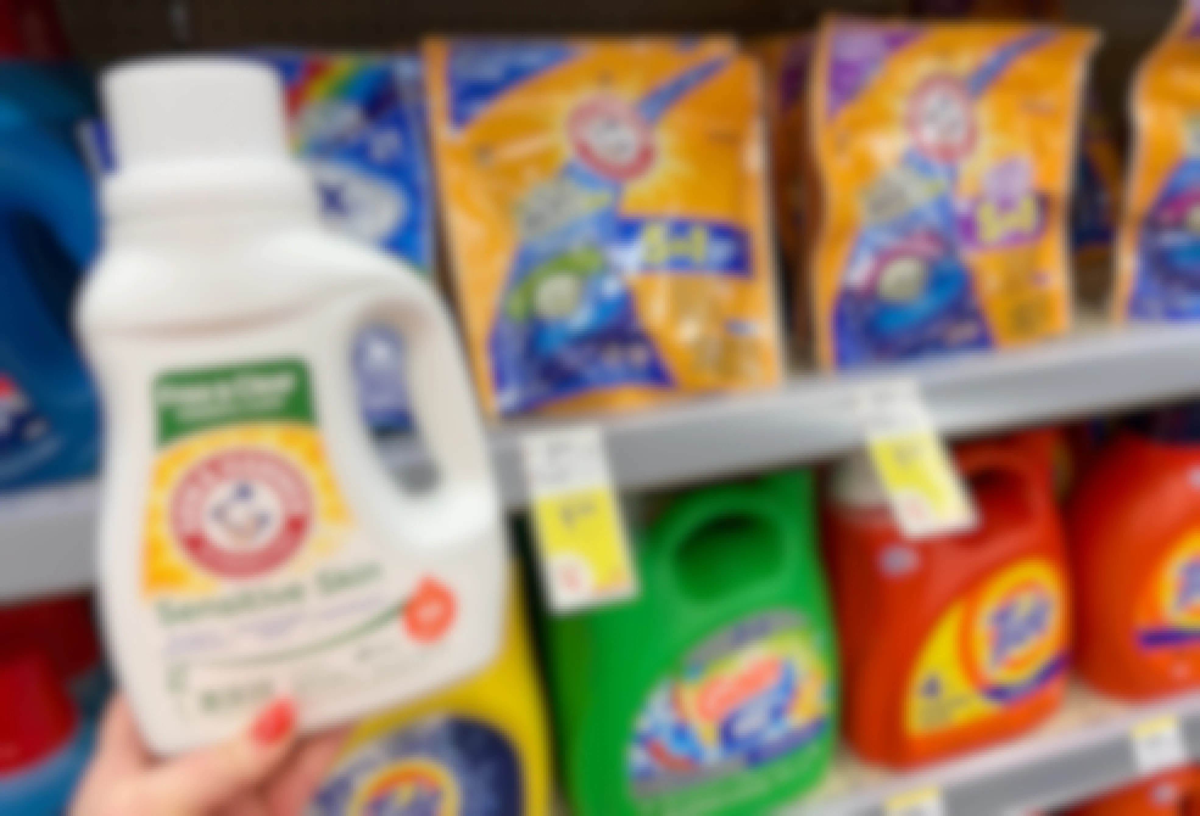 hand holding arm and hammer laundry detergent in front of a shelf with sale tags