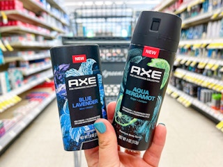 Someone holding Axe Blue Lavender deodorant stick and Aqua Bergamot body spray in Walgreens
