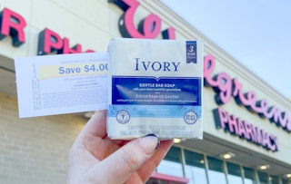 hand holding bars of ivory soap in front of a walgreens store with a register reward