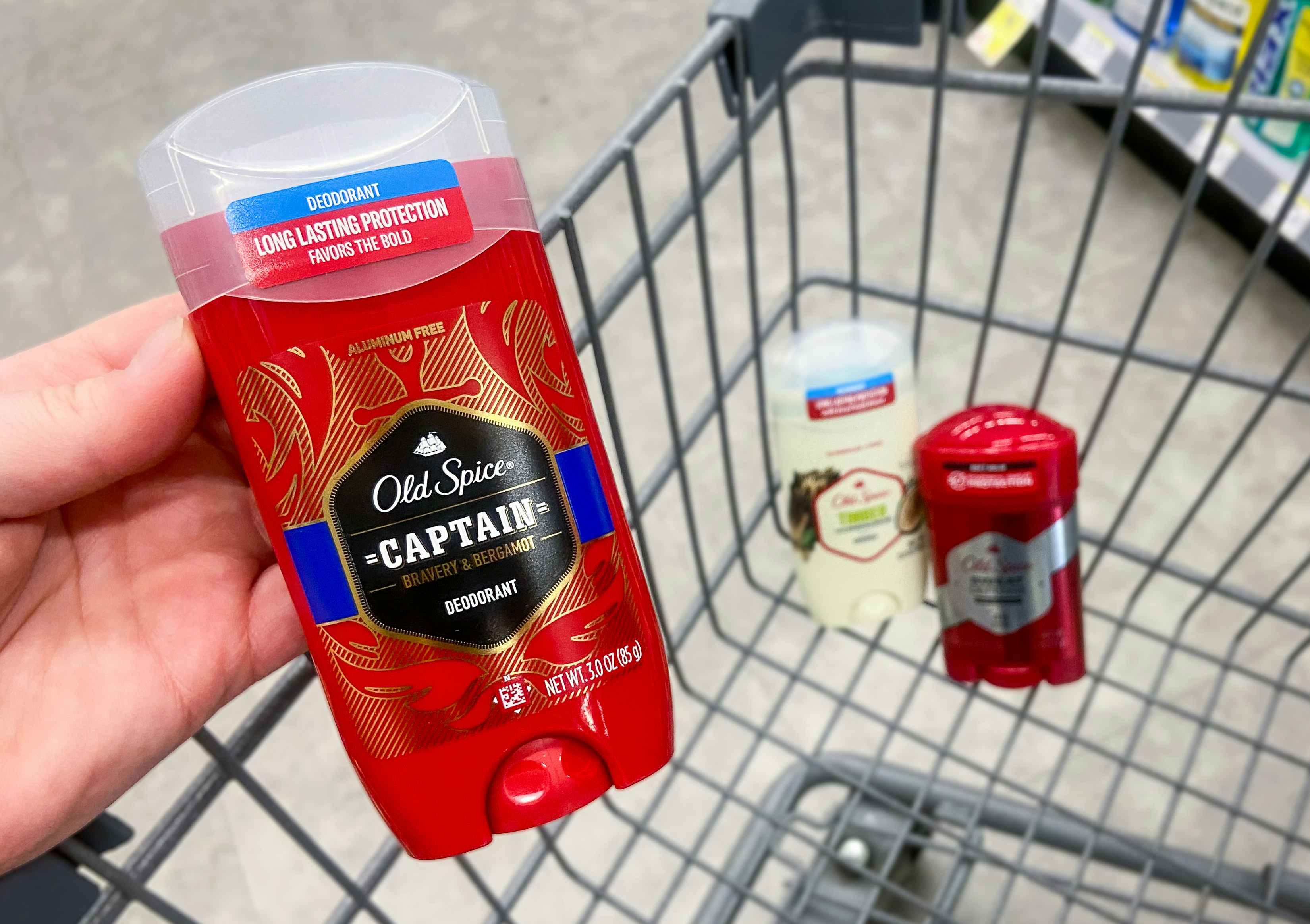 hand holding a stick of old spice deodorant and a walgreens shopping cart