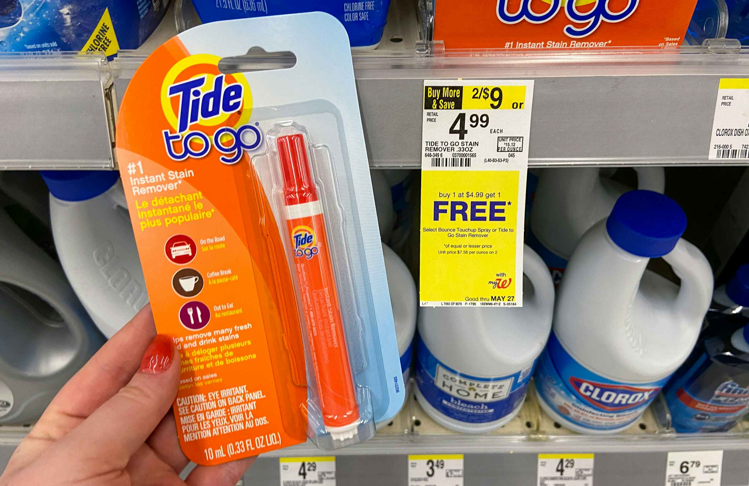 hand holding Tide to go stain eraser pen by a walgreens sale tag