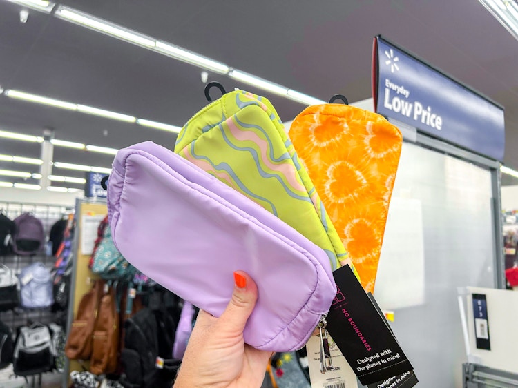 a person holding up three belt bags from walmart