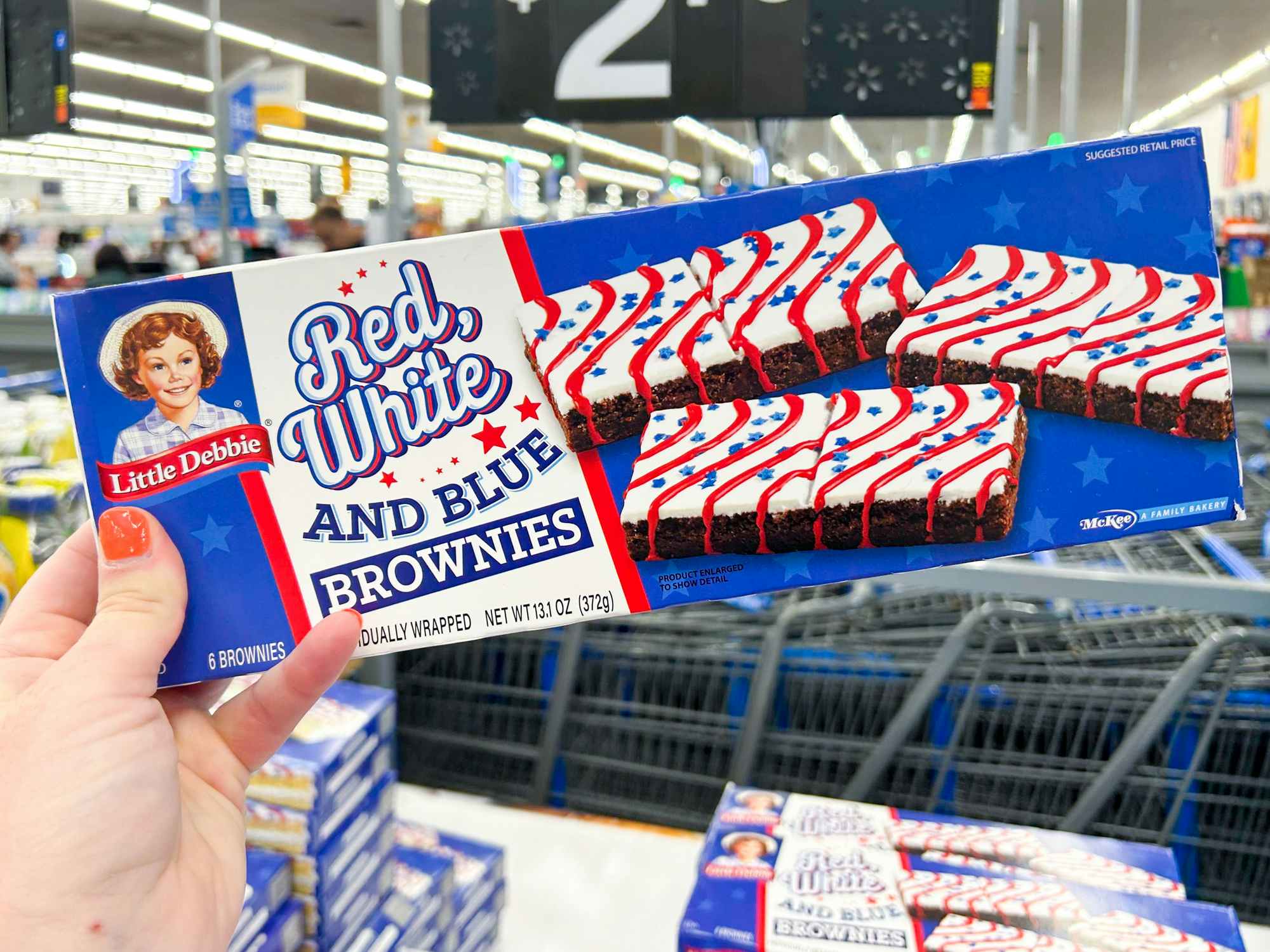 Someone holding up a box of Red White and Blue Little Debbie brownies in Walmart