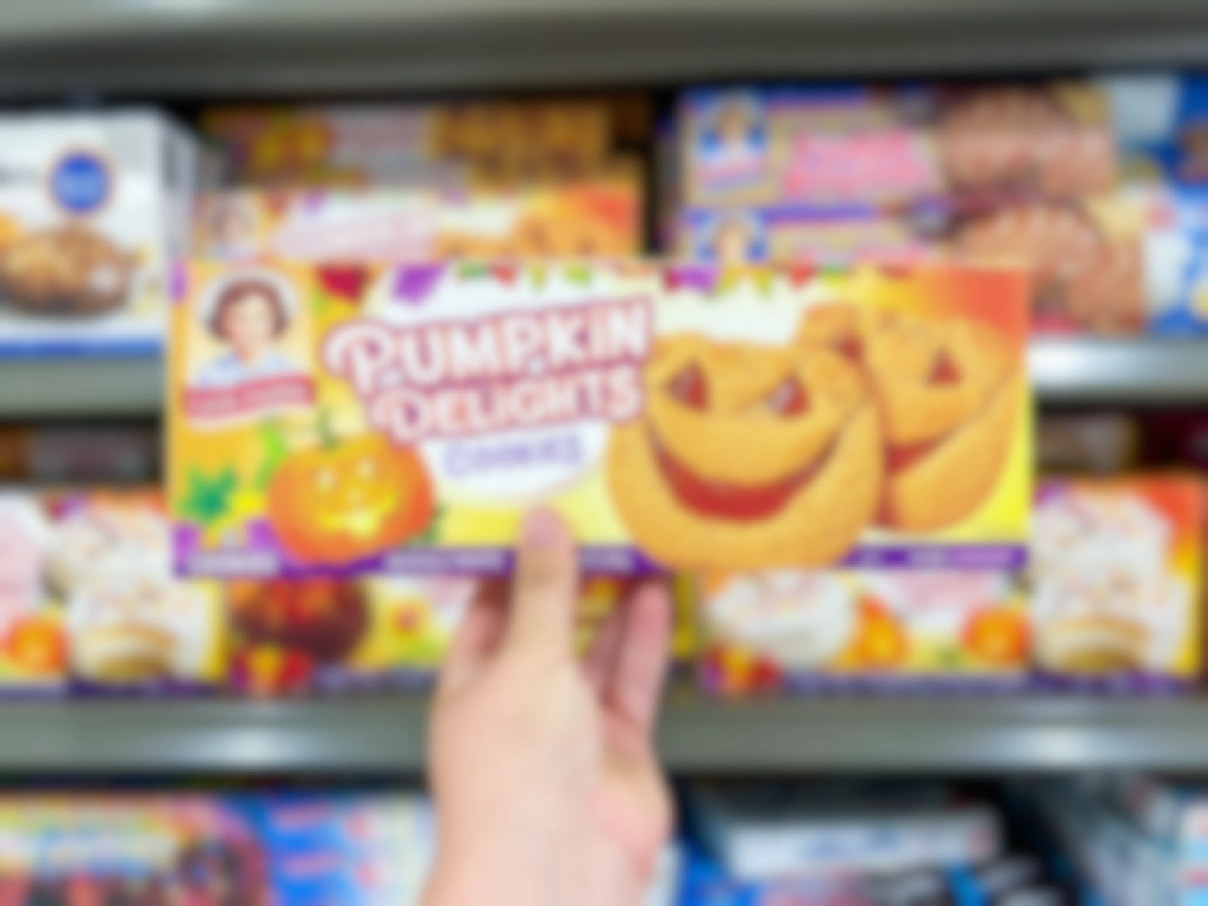 someone holding up a box of Little Debbie pumpkin delights cookies in Walmart