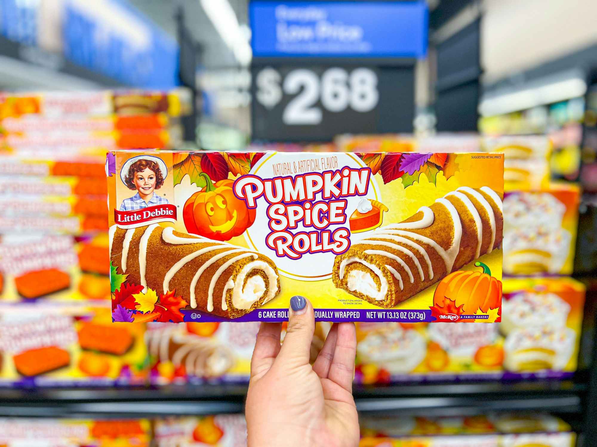 someone holding up a box of Little Debbie pumpkin spice rolls in Walmart