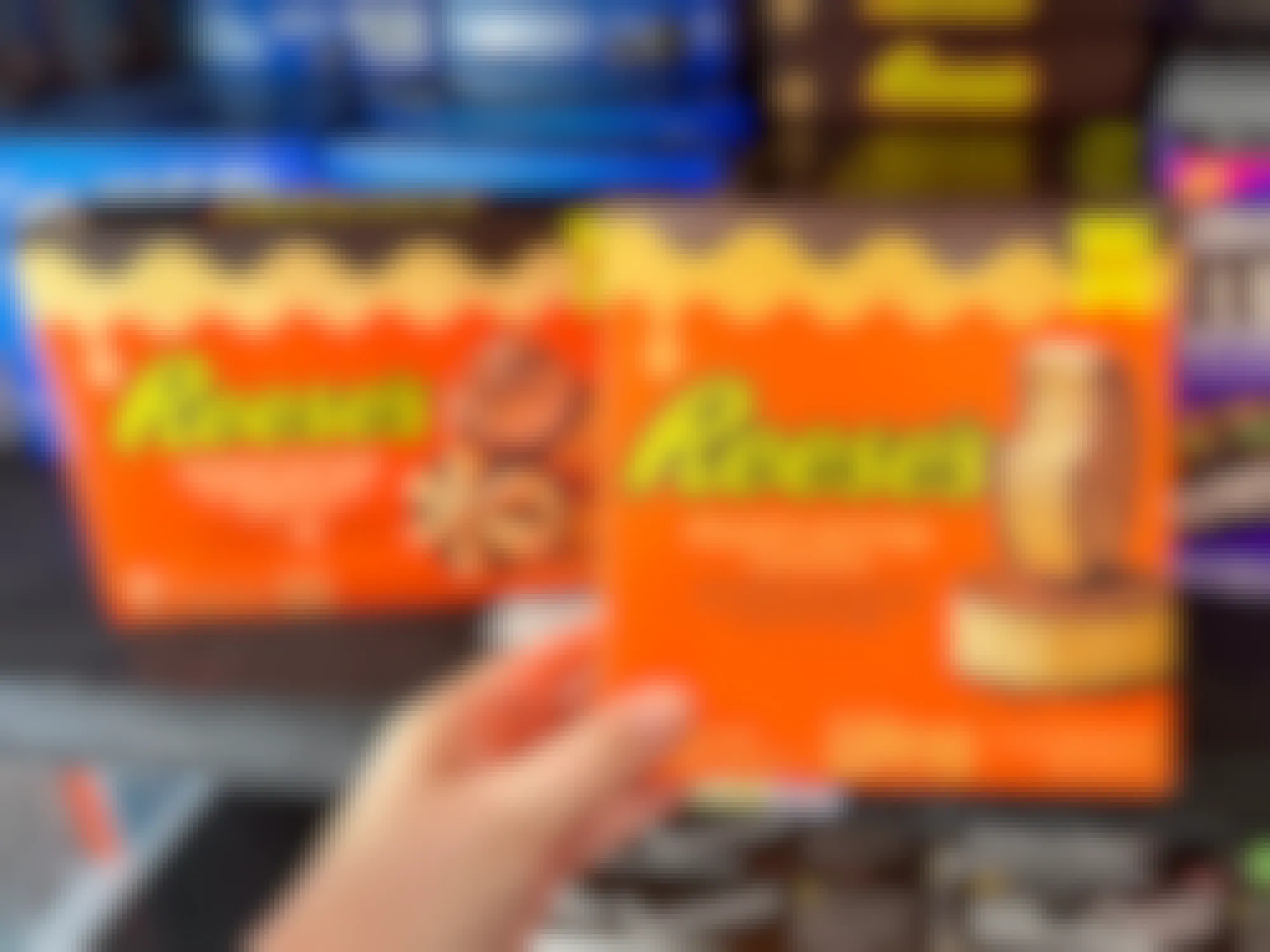Someone holding a box of Reese's Peanut Butter ice cream sandwiches next to a box of Reese's Peanut Butter Chocolate ice cream cones