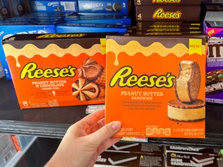 Someone holding a box of Reese's Peanut Butter ice cream sandwiches next to a box of Reese's Peanut Butter Chocolate ice cream cones