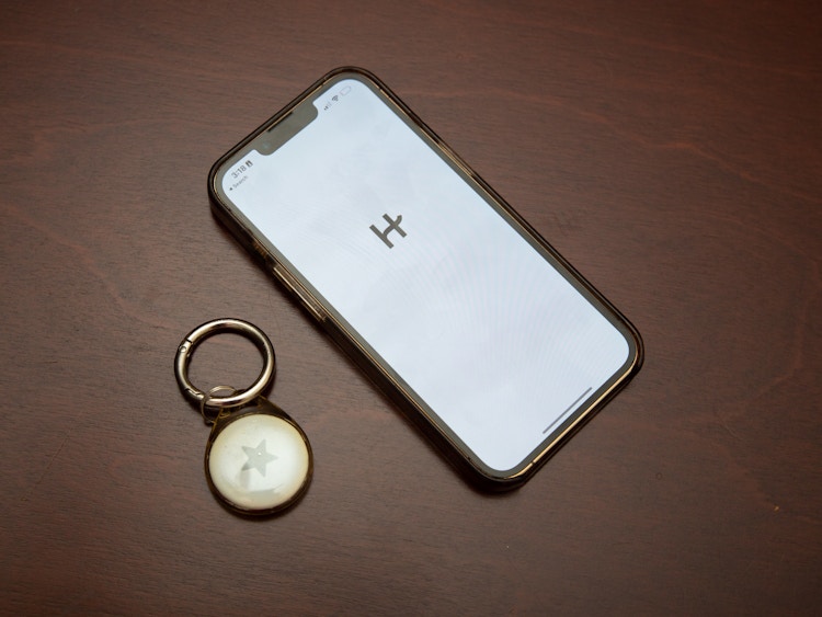 Phone with the Hinge dating app open with an airtag next to it