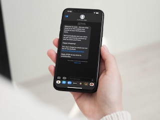 Someone holding a phone showing a text message from subscribing to Aisle text alerts