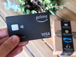Someone holding an Amazon Prime credit card next to an Amazon box