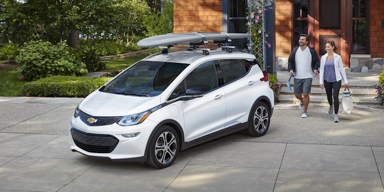 Chevrolet Bolt 2023 with people looking at it outside a home.