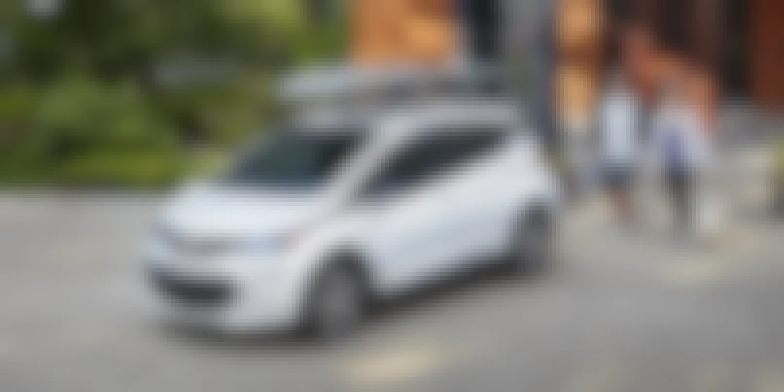 Chevrolet Bolt 2023 with people looking at it outside a home.