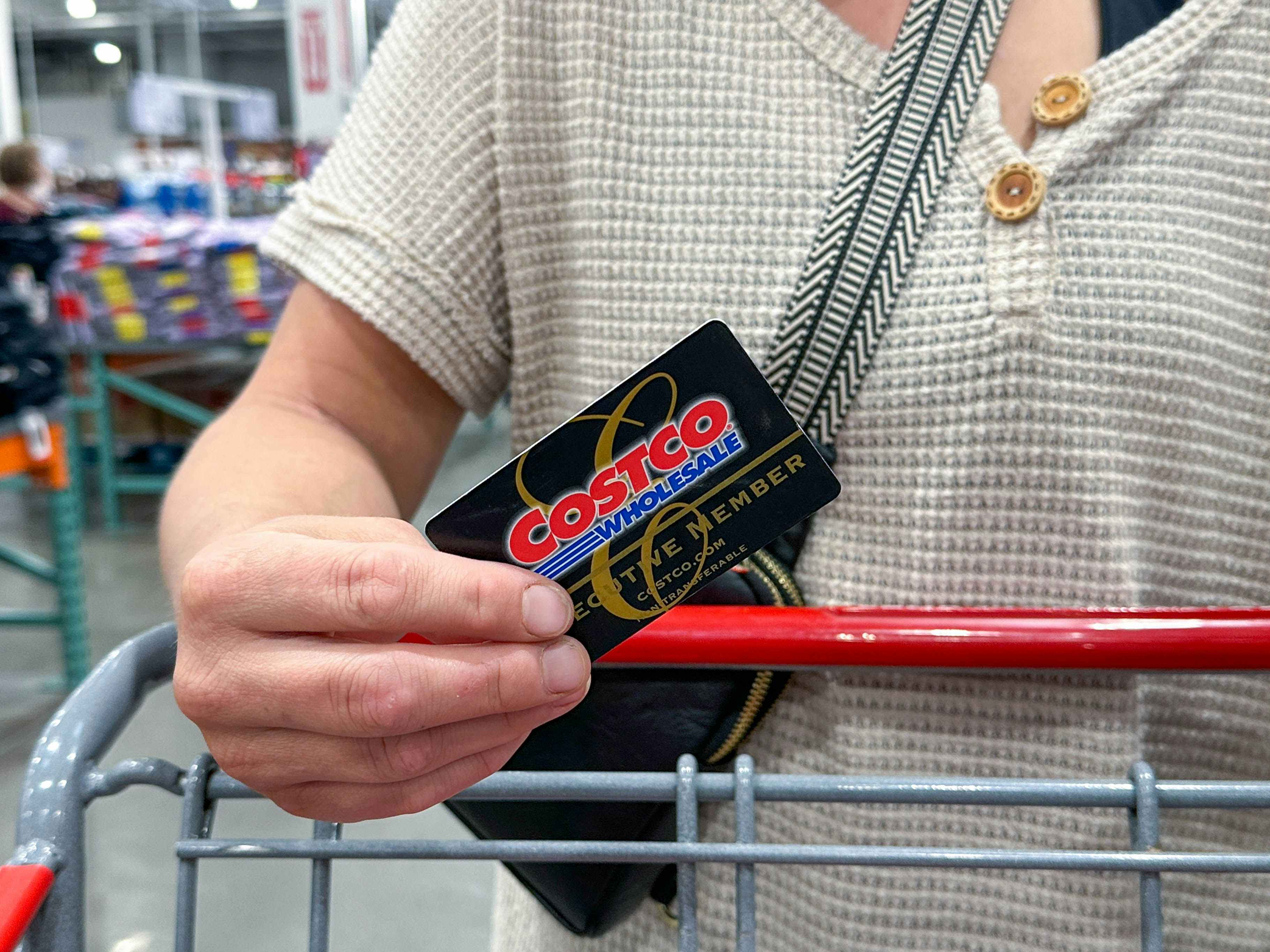 a person holding a costco cart while psuhing cart