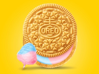A cotton candy Oreo cookie with blue and pink creme on a bright yellow background