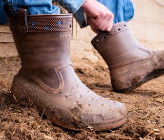 Someone putting on a pair of Classic Western Boots from the Croc and Huckberry collab