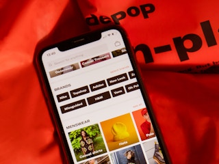 A close up on a phone sitting on top of a Depop bag, displaying the Depop app