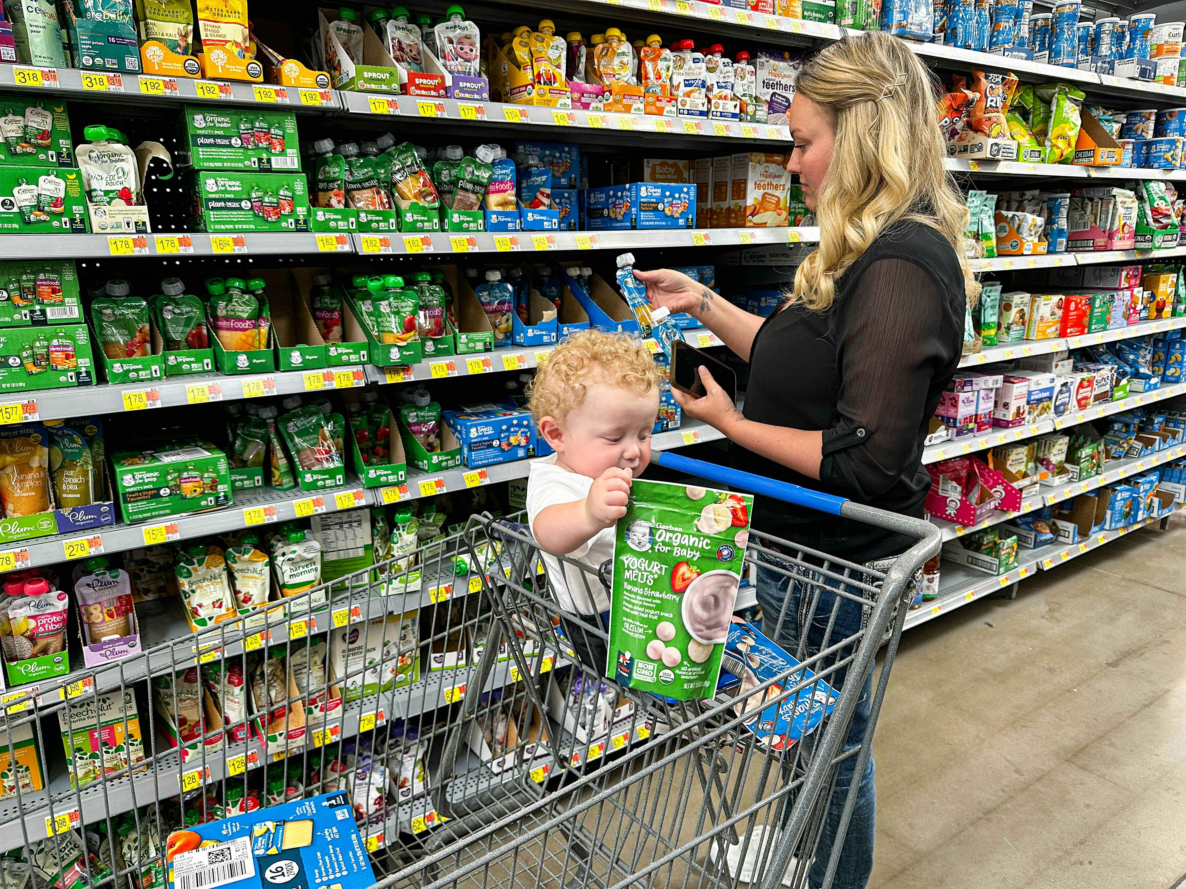 a woman shopping for gerber baby food in walmart with a baby
