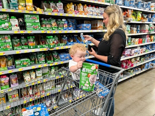 a woman shopping for gerber baby food in walmart with a baby