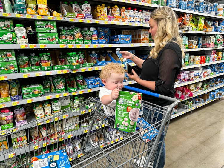 a woman shopping for gerber baby food in walmart with a baby