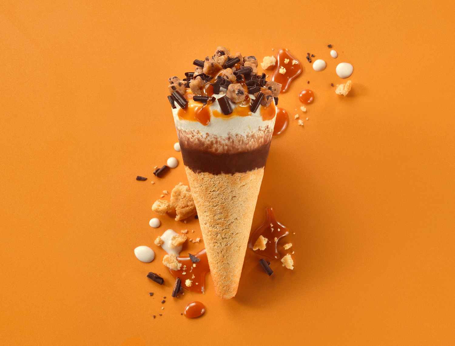 Cookiebutter cone with ice cream chocolate and caramel on an orange background
