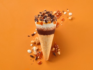 Cookiebutter cone with ice cream chocolate and caramel on an orange background