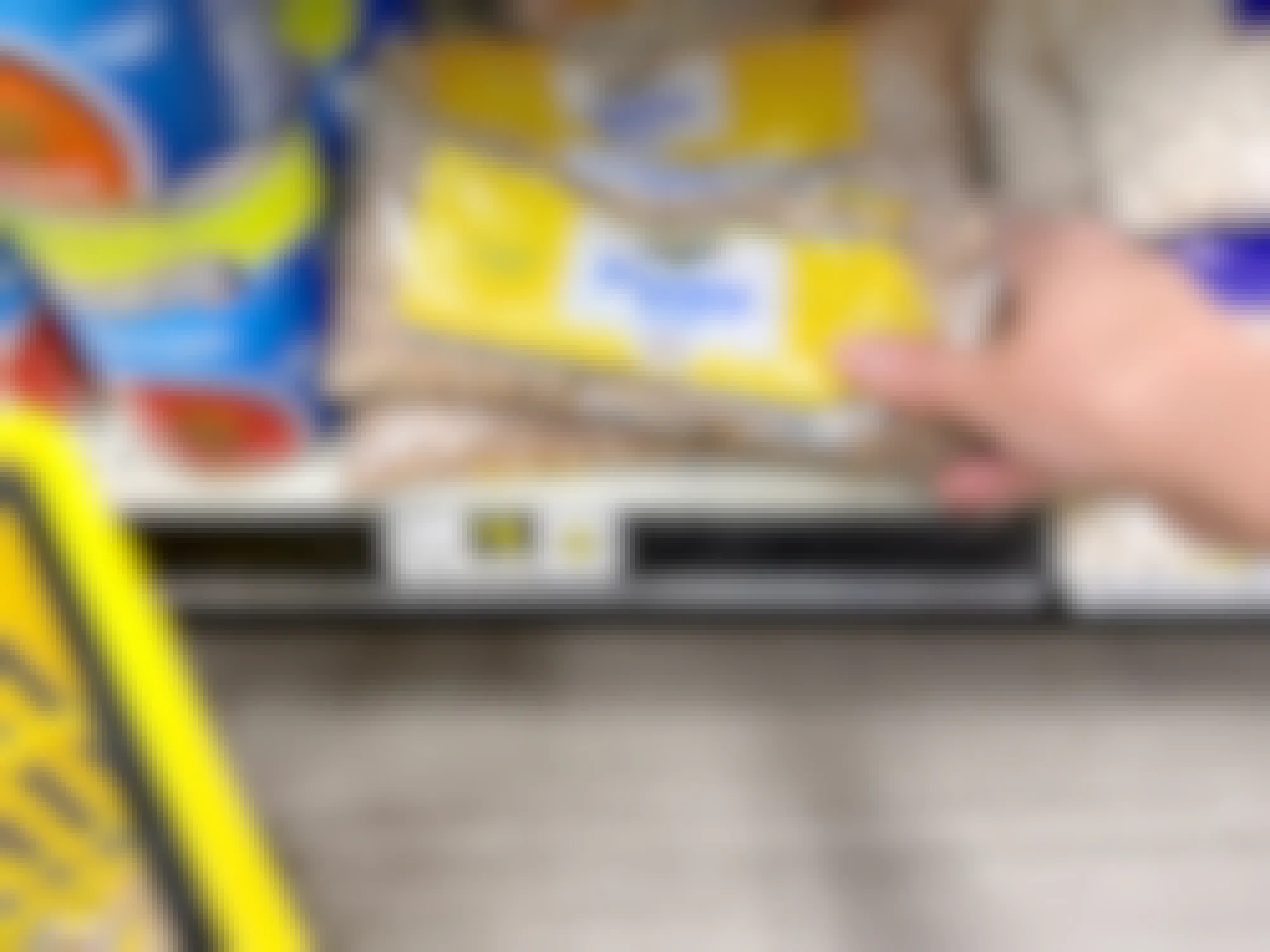 person grabbing a 16 ounce bag of dry pinto beans from a dollar general shelf for one dollar
