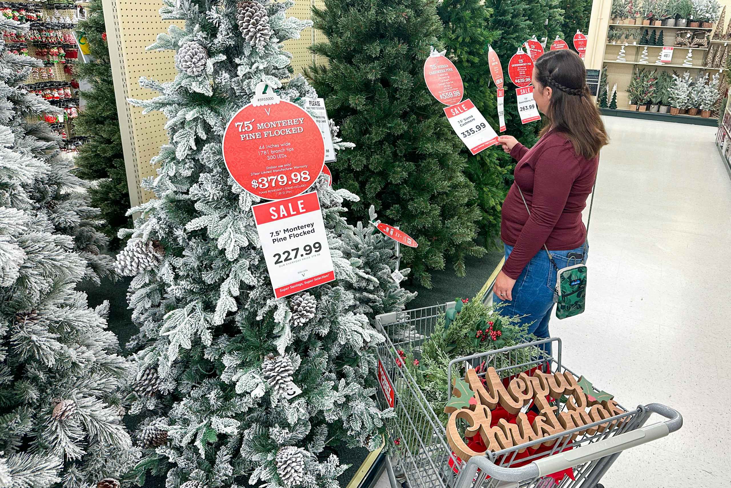 a woman looking at artificial trees in hobby lobby