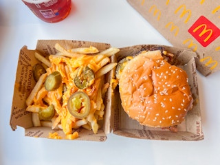 Jalepeno and nacho cheese of fries next to a burger fro mcdonalds