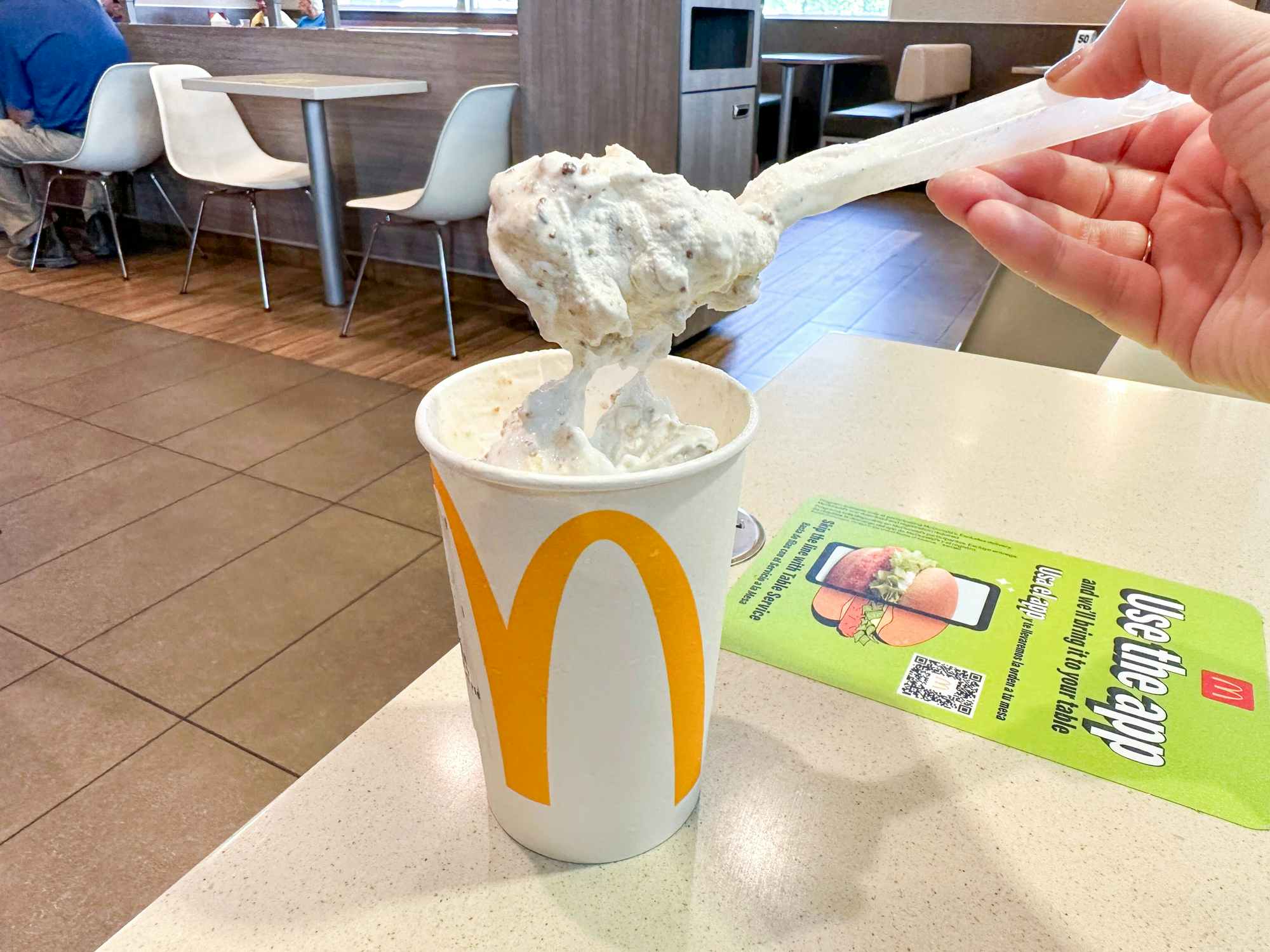 Someone taking a spoonful from a Peanut Butter Crunch McFlurry at McDonald's