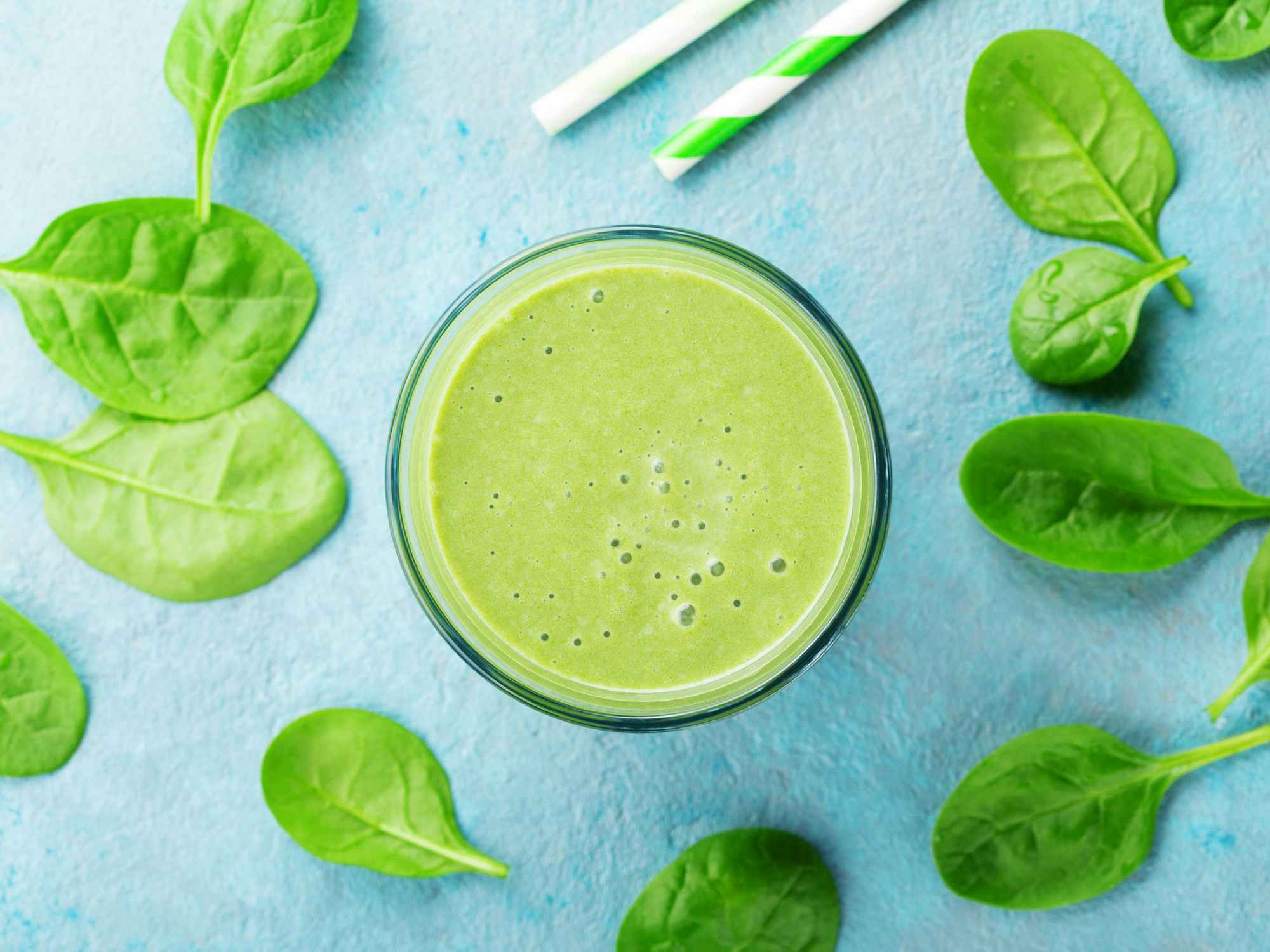 green monster smoothie with baby spinach leaves and straws
