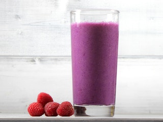 purple people eater smoothie in a glass with raspberries