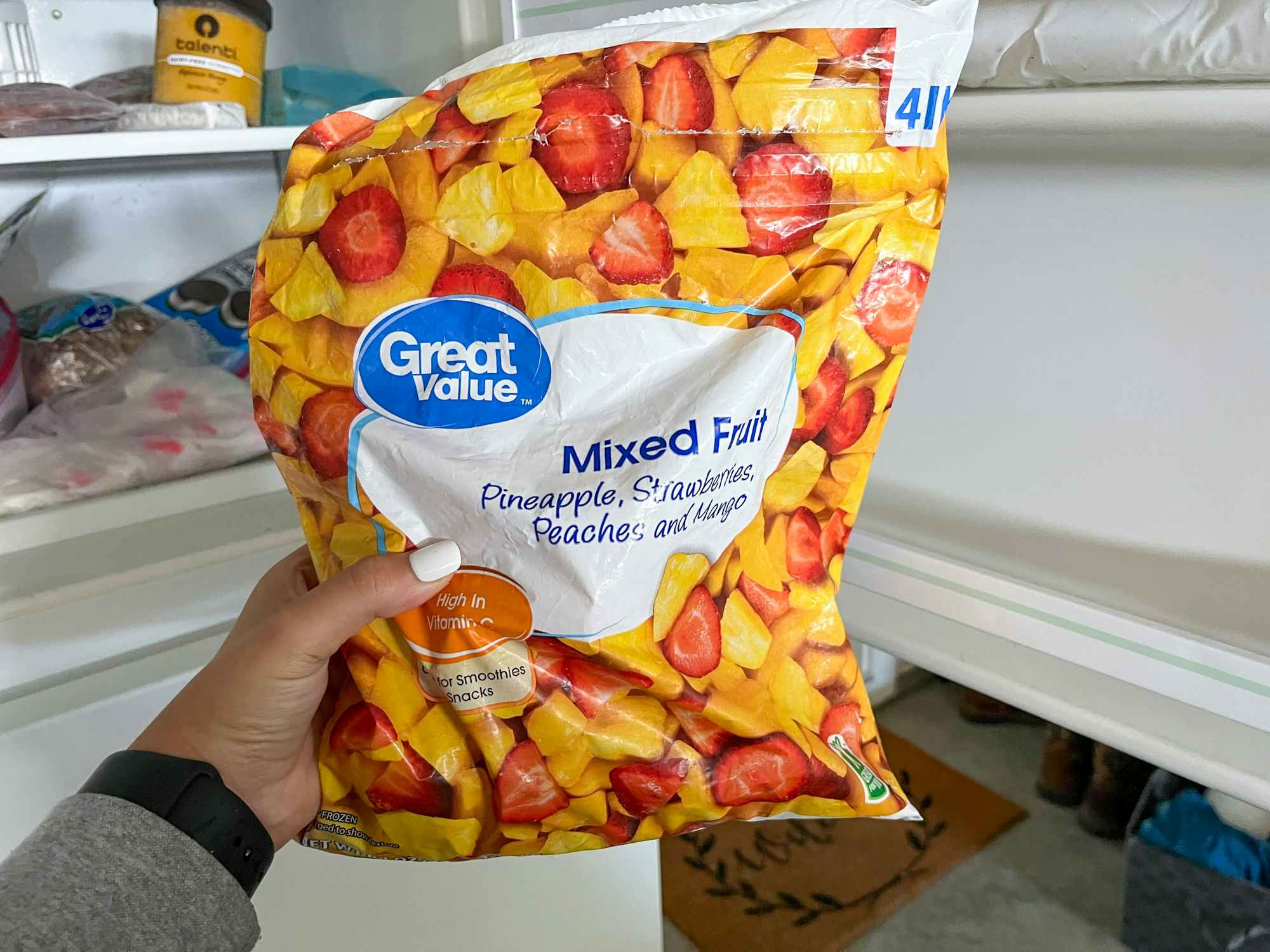 Someone taking a recalled bag of frozen mixed fruit out of their freezer