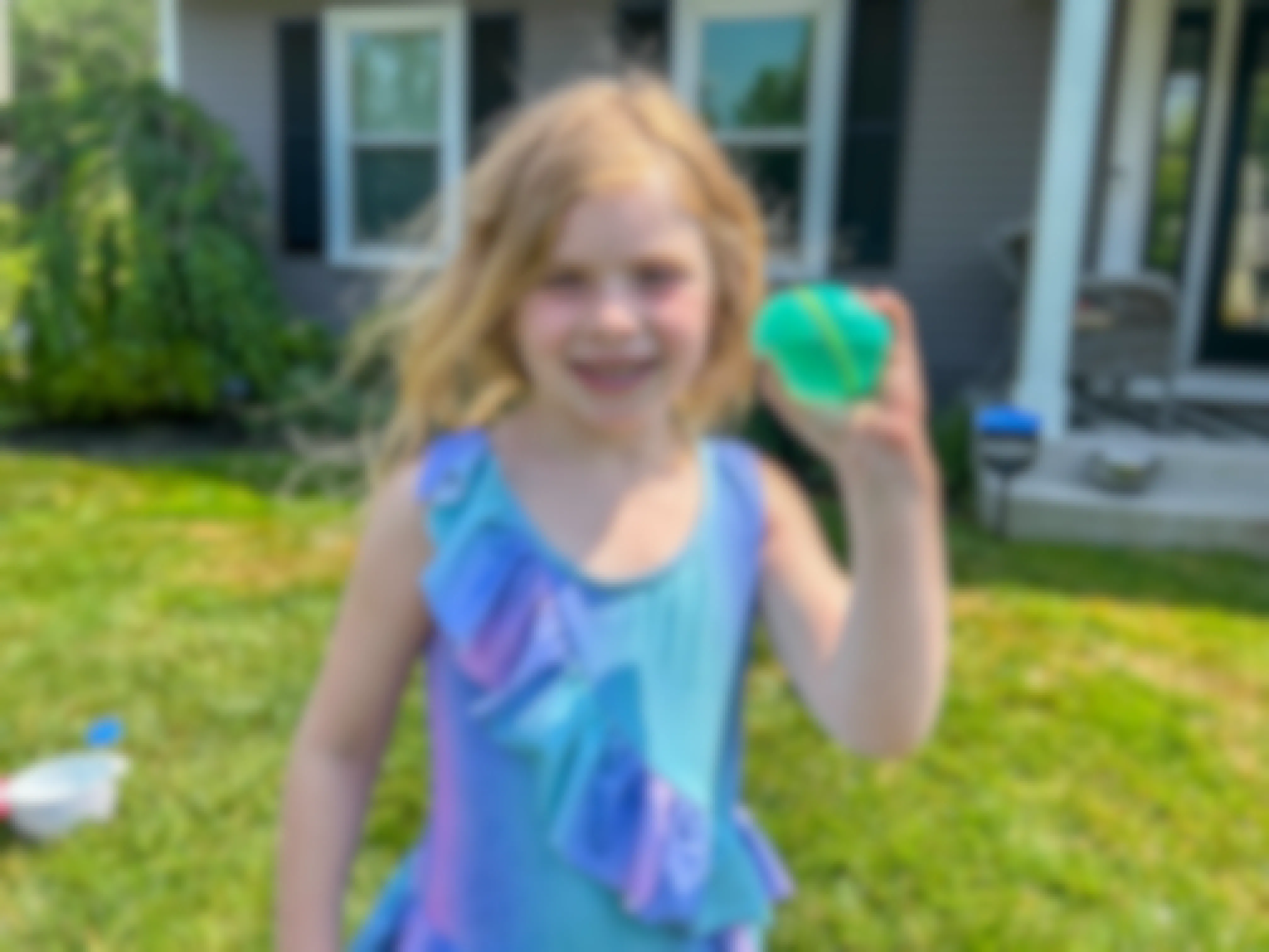 a child smiling while holding a reusable water balloon 