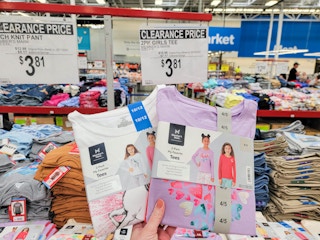 hand holding kids tee 2-packs by a sign for $3.81