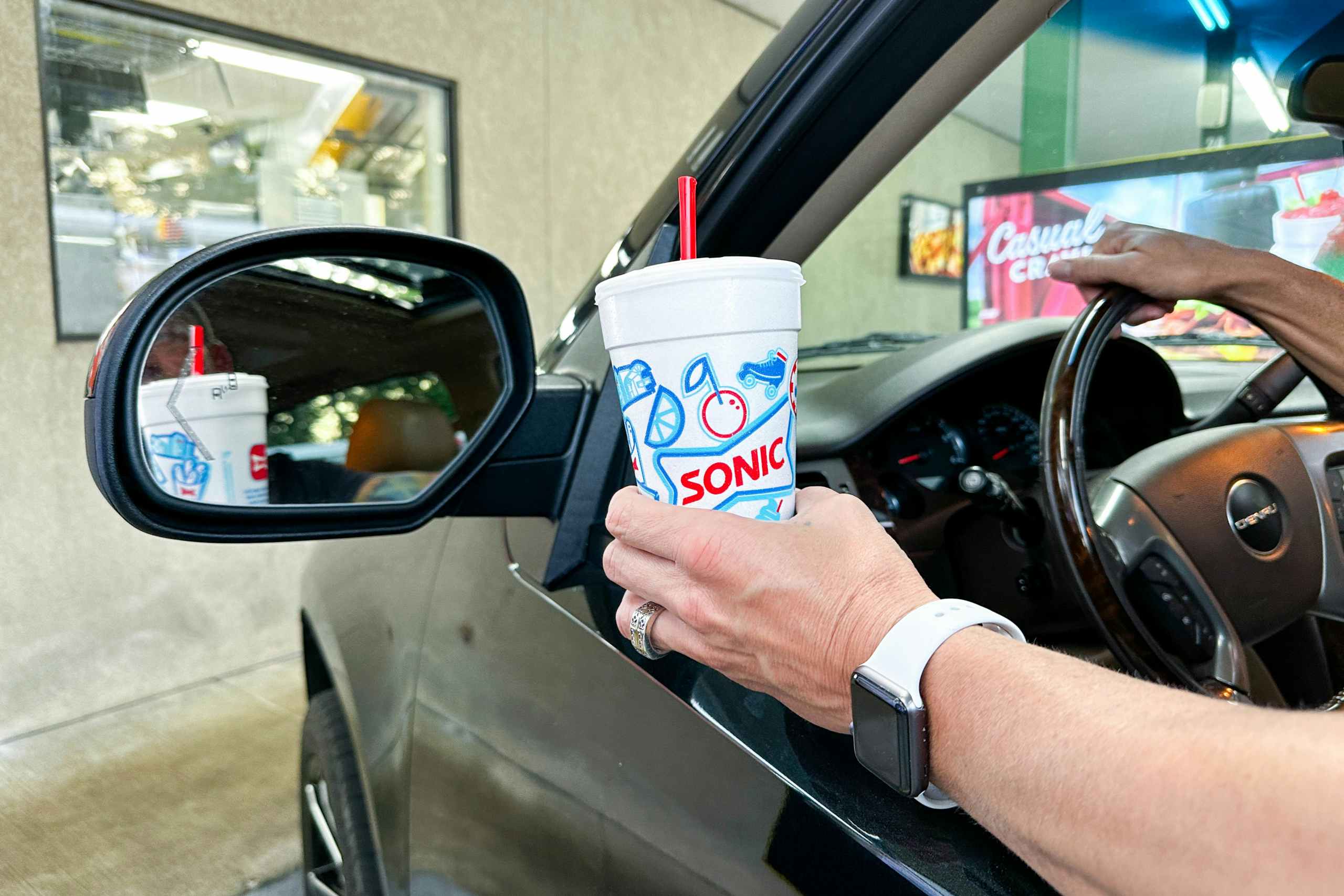 a person holding a sonic drink outside a car window