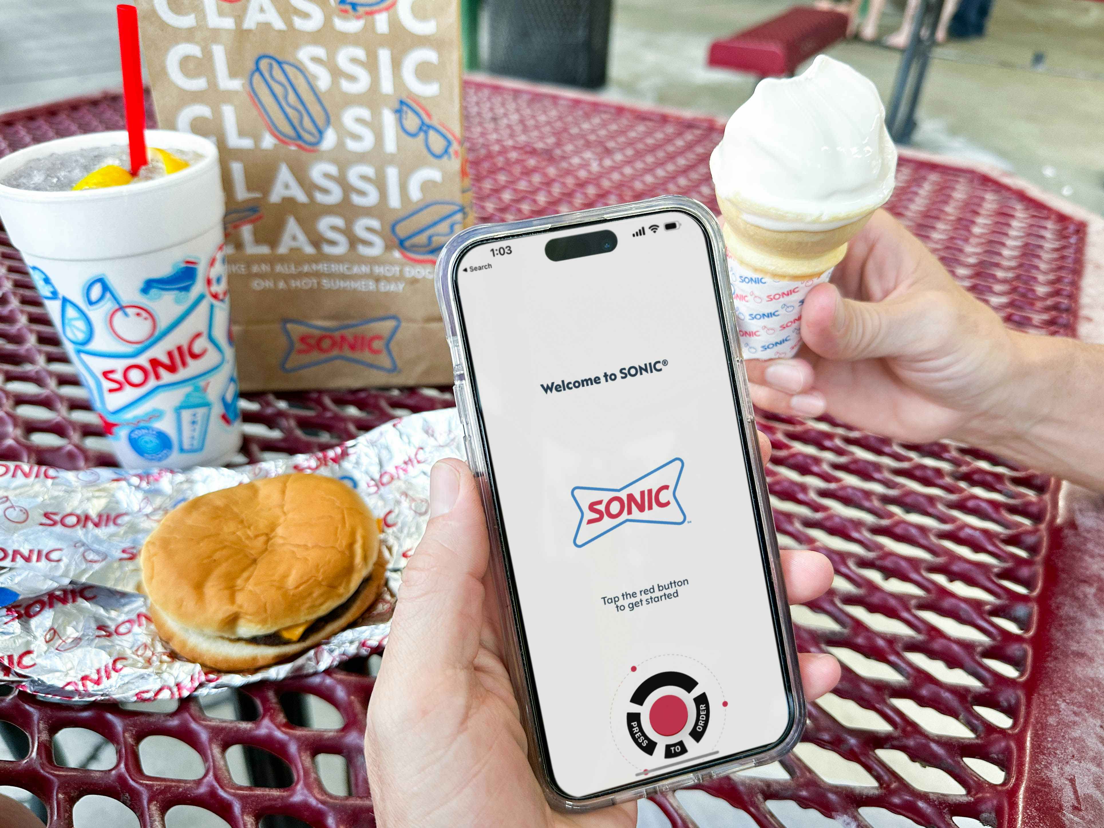a person holding sonic food while on phone with sonic app