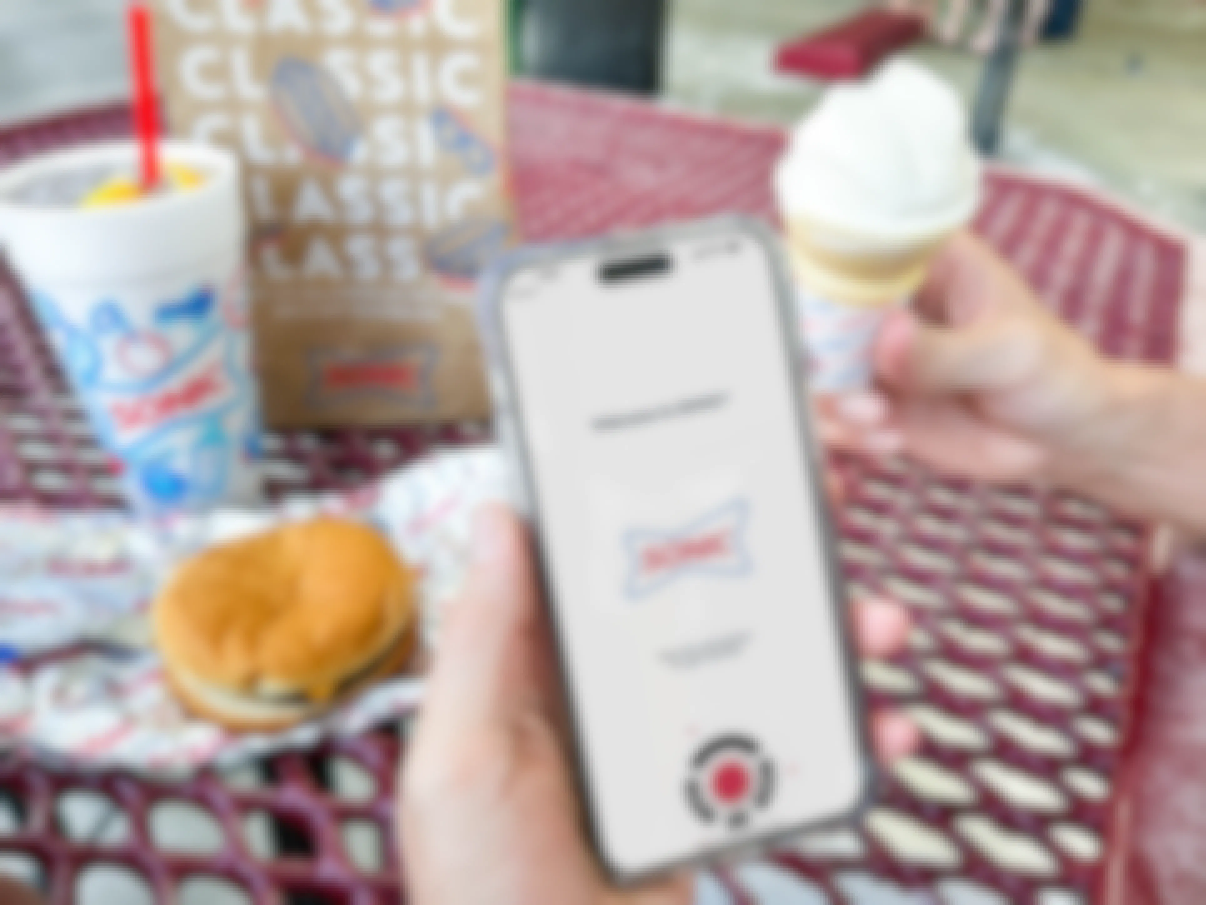 a person holding sonic food while on phone with sonic app