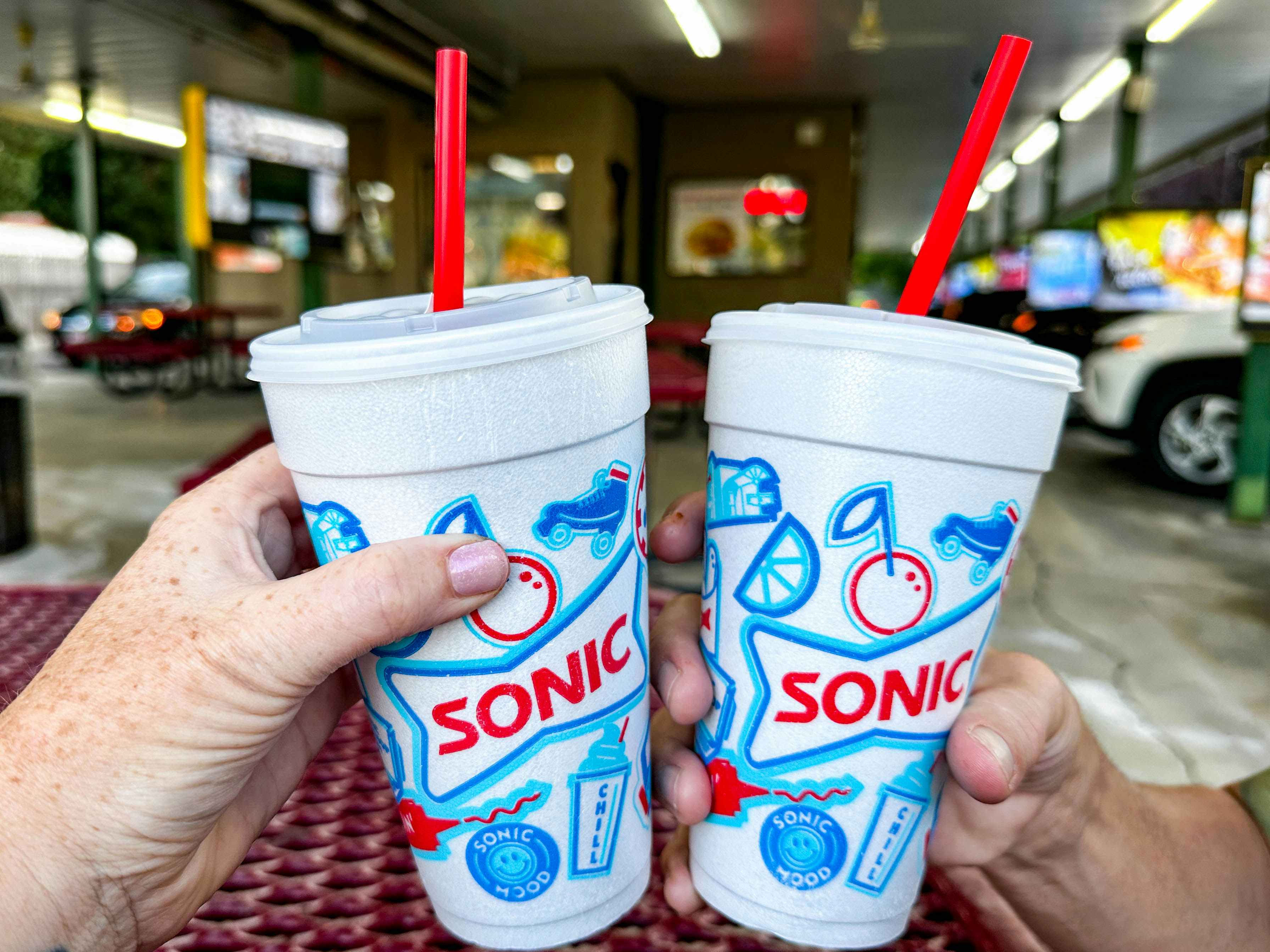 two people holding sonic drinks outside sonic