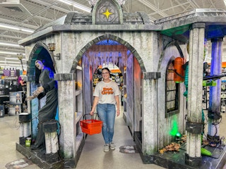 a person standing inside of a spirit halloween while smiling