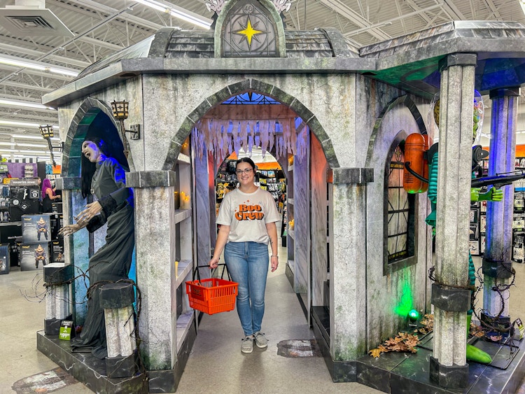 a person standing inside of a spirit halloween while smiling