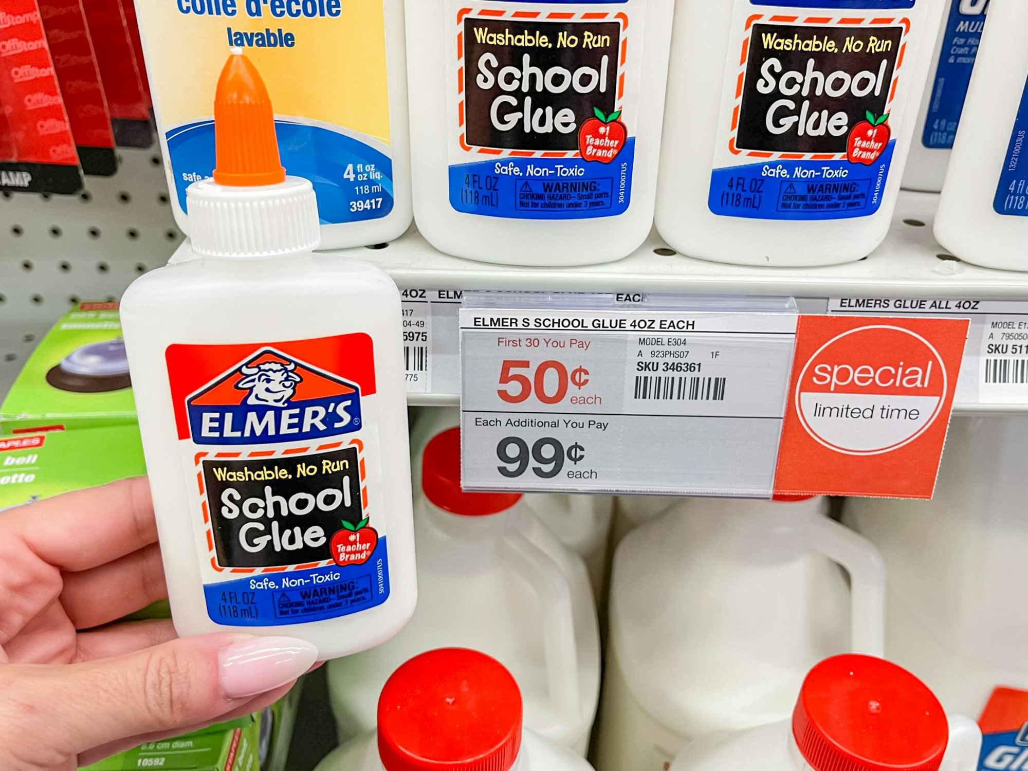 Someone holding a bottle of Elmer's glue next to a price tag for 50¢ at Staples