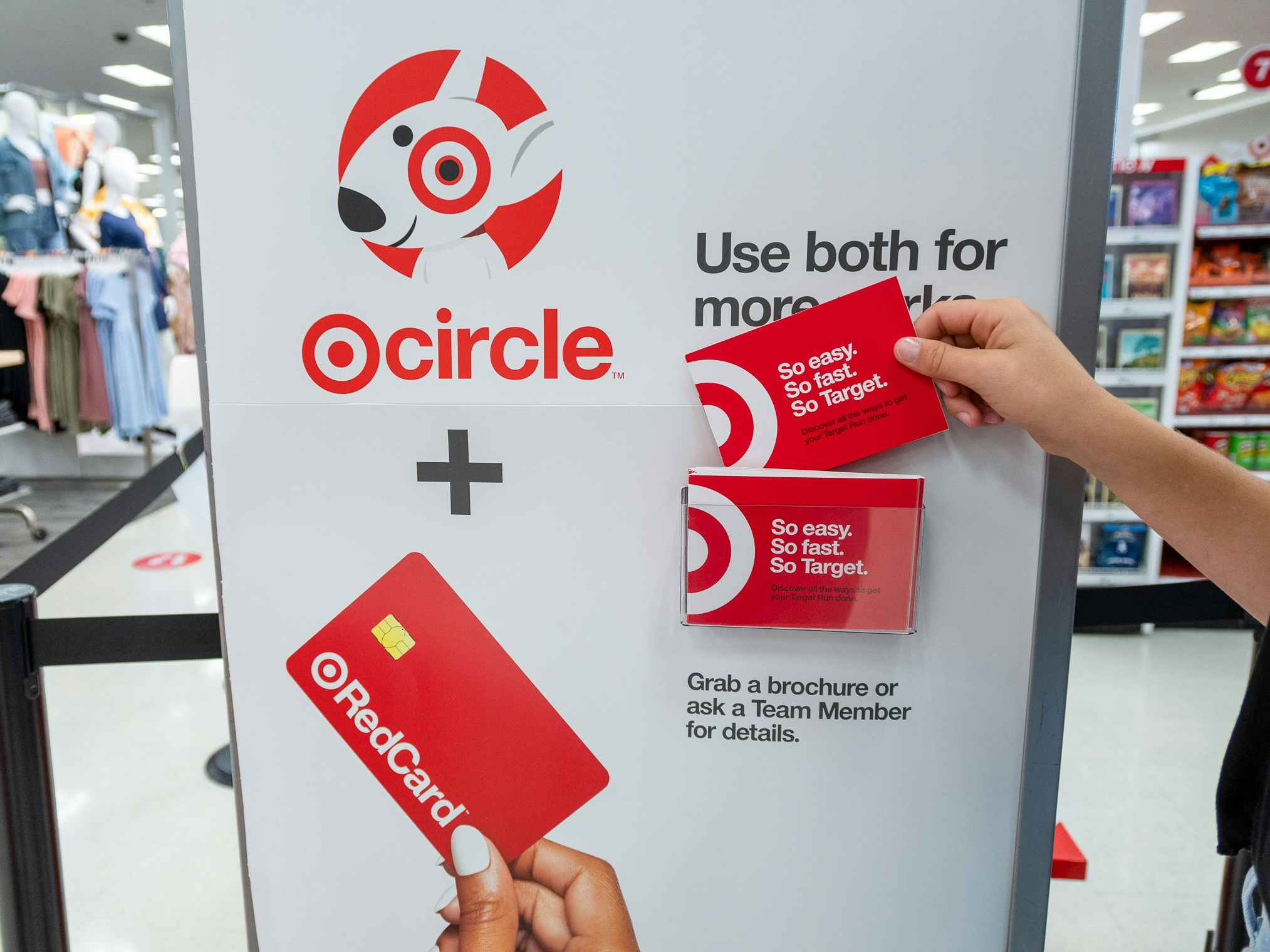 A person taking a brochure from the Target Circle and RedCard information stand inside Target.