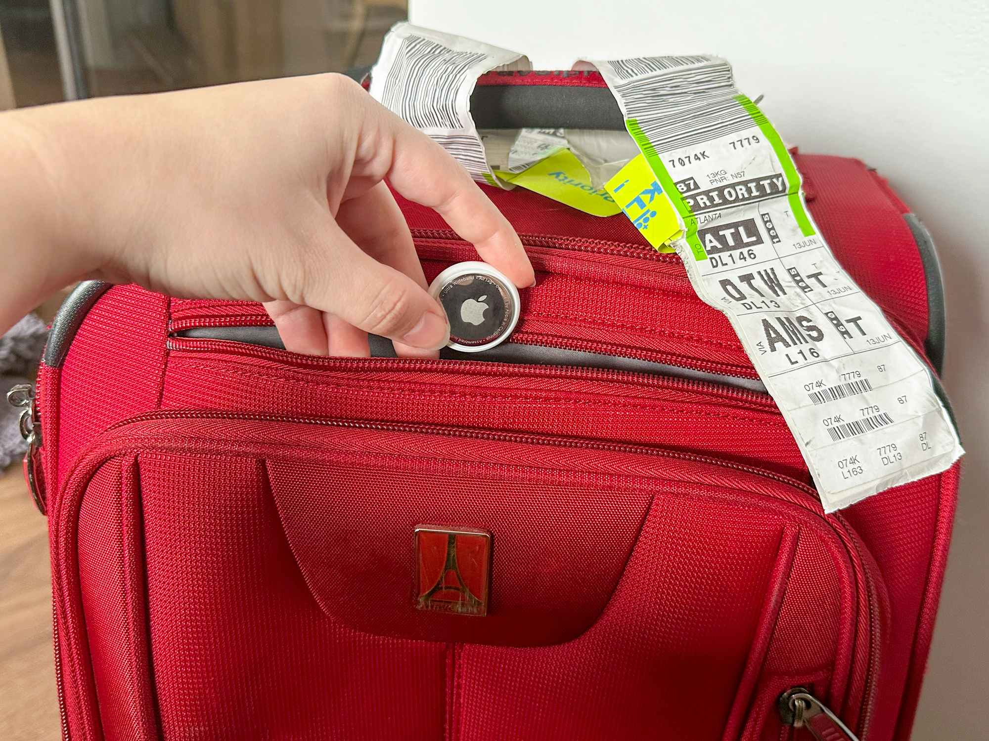 Someone putting an airtag into their suitcase to keep track of it